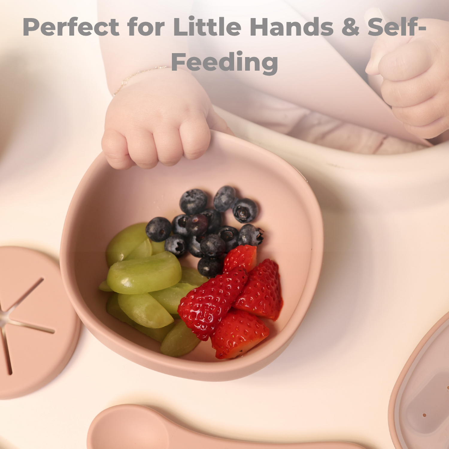 Child's hand holding a pink bowl with fruits, with text 'Perfect for Little Hands & Self-Feeding'.