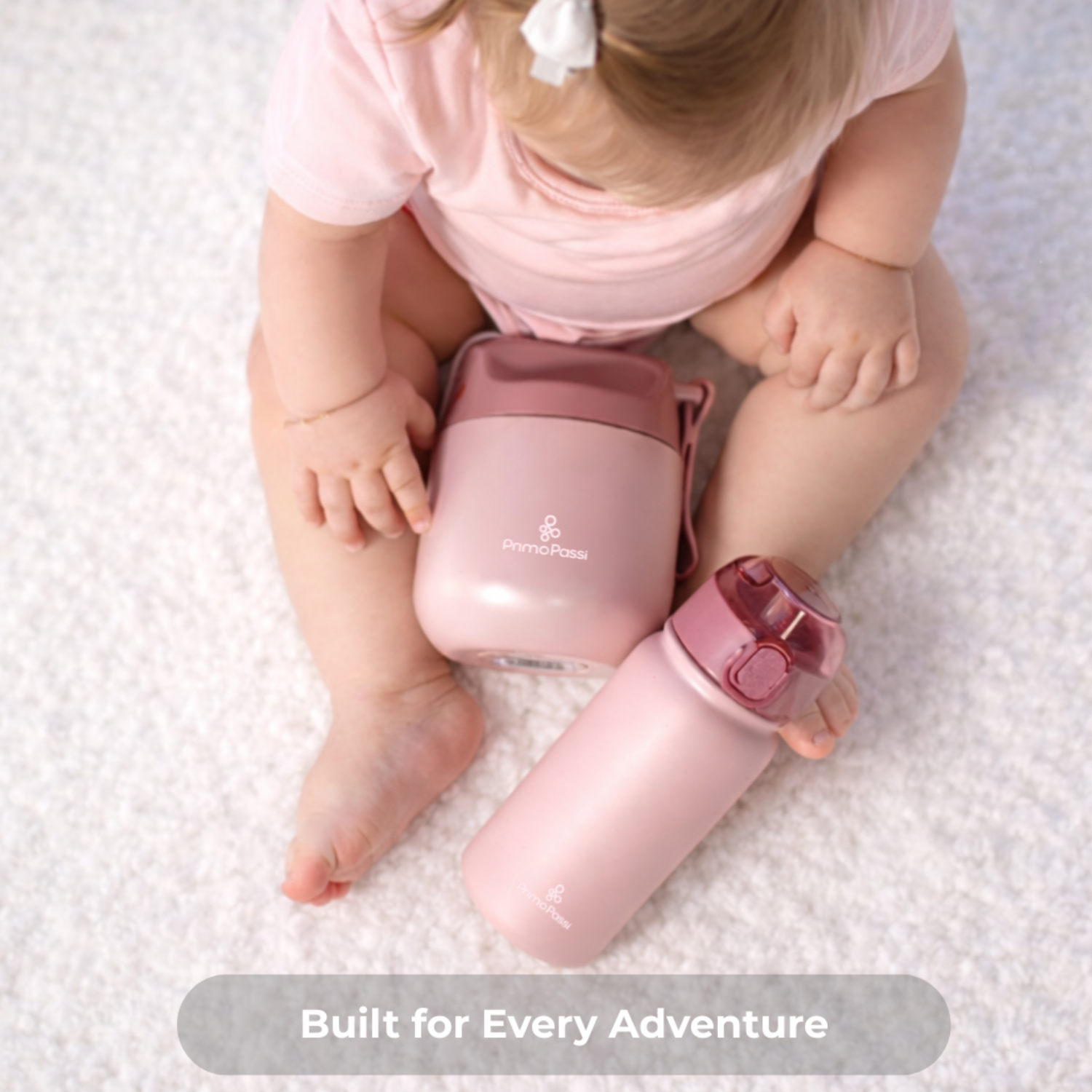 Child holding a pink insulated water bottle and food jar with a visible brand logo on a white textured background