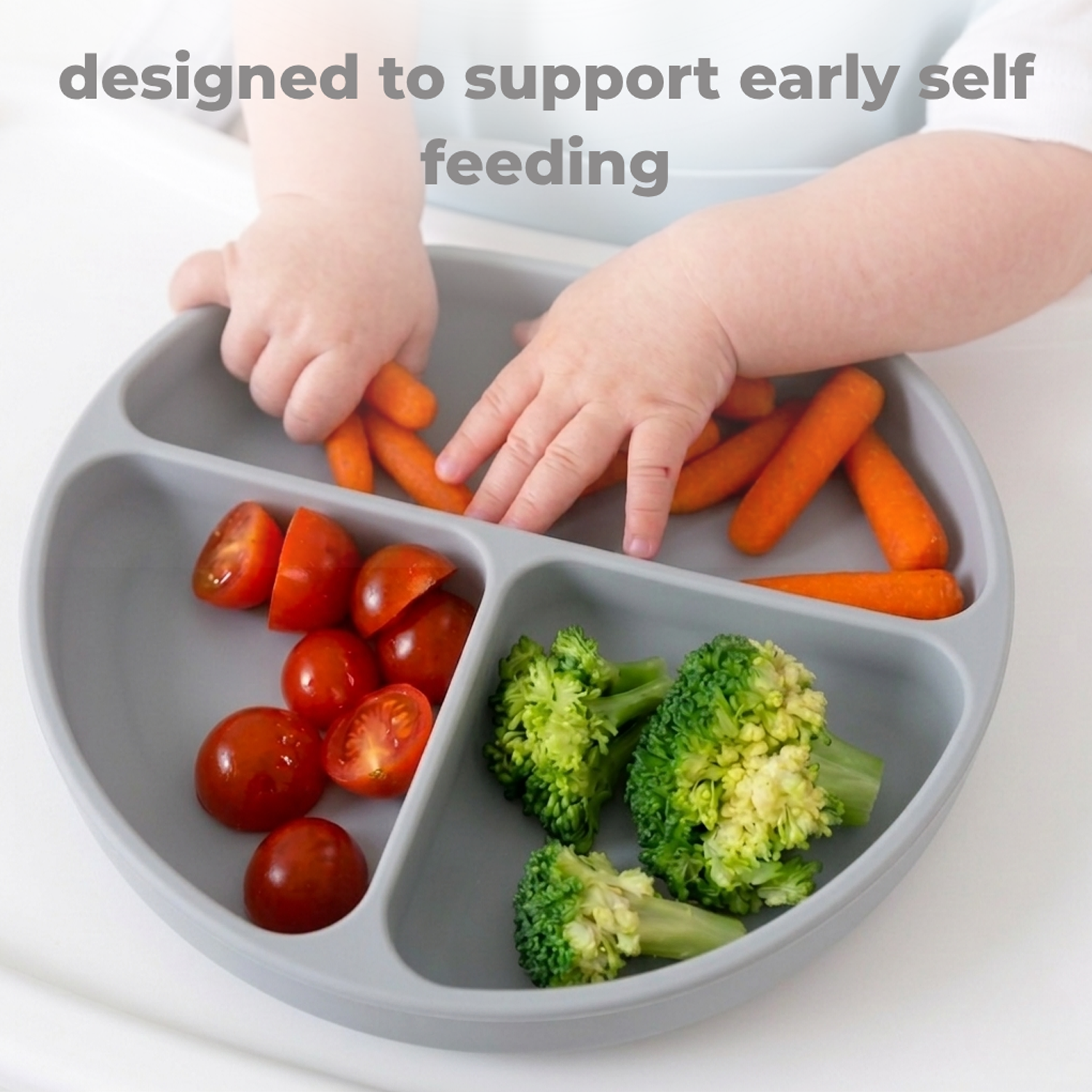 Children's hands reaching vegetables on a divided plate with text 'designed to support early self feeding'.