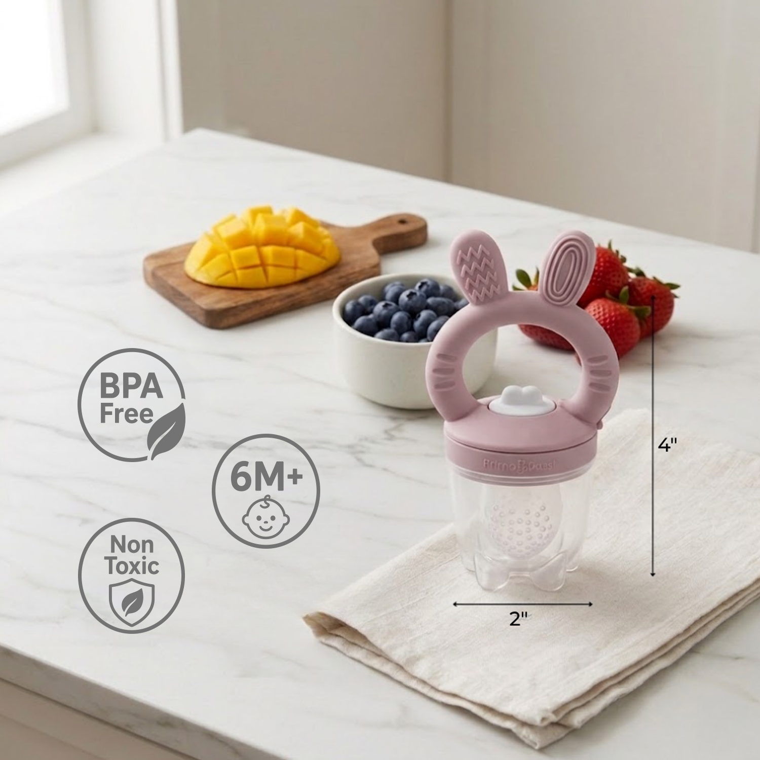 Pink baby teether and food feeder with bunny ears on a marble surface with fruits and vegetables.