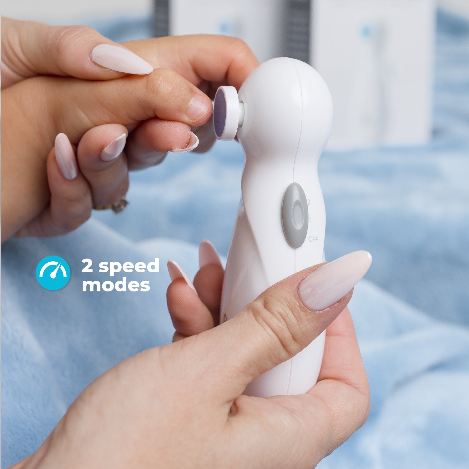 Hands holding a white electric nail filer and a baby's hand with the thext: 2 speed modes
