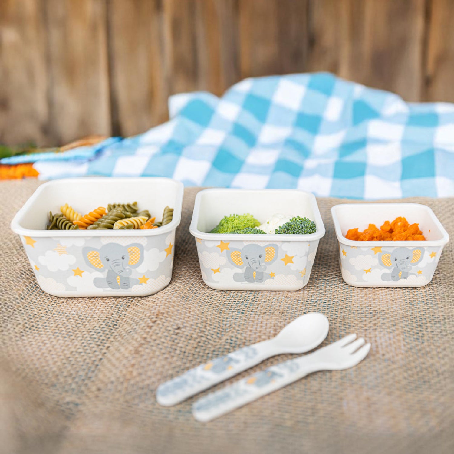 Three bamboo fiber food storage containers filled with baby-friendly foods, including pasta, broccoli, and a vegetable puree, displayed with a matching baby spoon and fork. Reusable containers are perfect for storing and serving baby meals at home or on the go.