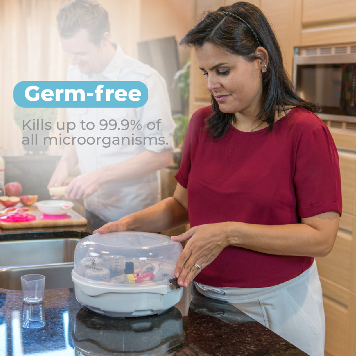Parent securing the Primo Passi microwave steam sterilizer on a kitchen countertop after sterilizing baby bottles and accessories, with text highlighting germ-free sterilization that kills up to 99.9% of microorganisms.