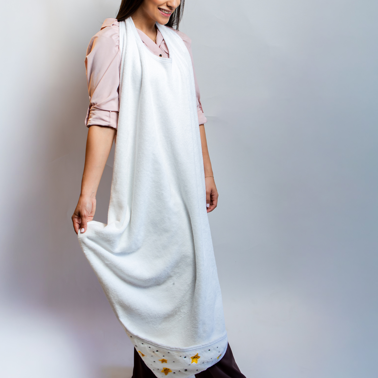 Adult wearing the Primo Passi Terry Hooded Towel in its apron-style design before bath time. Made from ultra-soft, highly absorbent 100% cotton, the extra-large towel protects clothing from splashes while keeping both hands free for safely bathing, lifting, and drying babies and young children up to 5 years old.