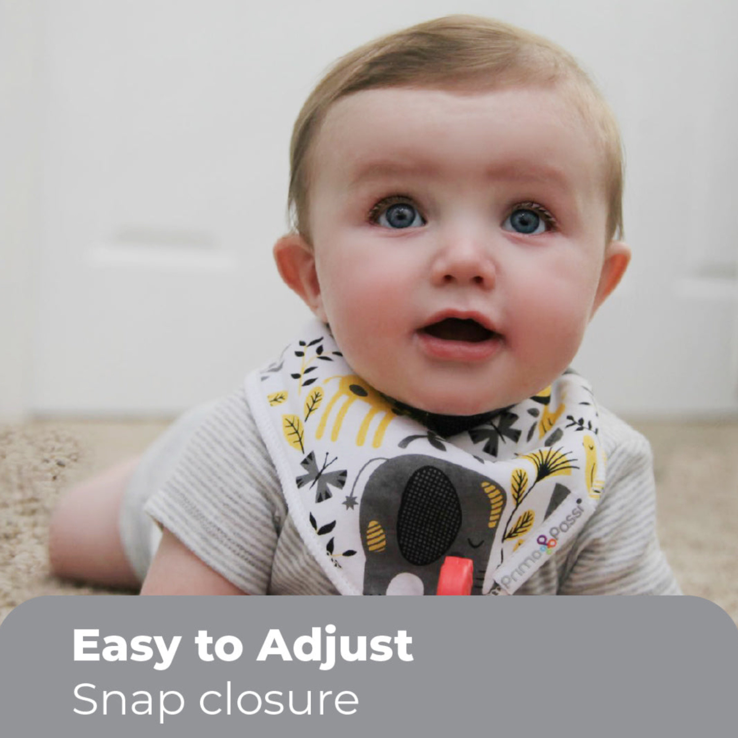 Baby wearing a Primo Passi patterned bandana bib with an adjustable snap closure. The soft, absorbent bib fits comfortably around the neck and helps keep clothing clean during feeding, drooling, and teething.