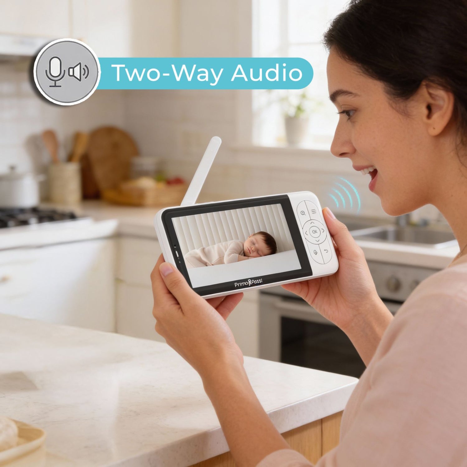 Woman using a baby monitor with two-way audio in a kitchen.