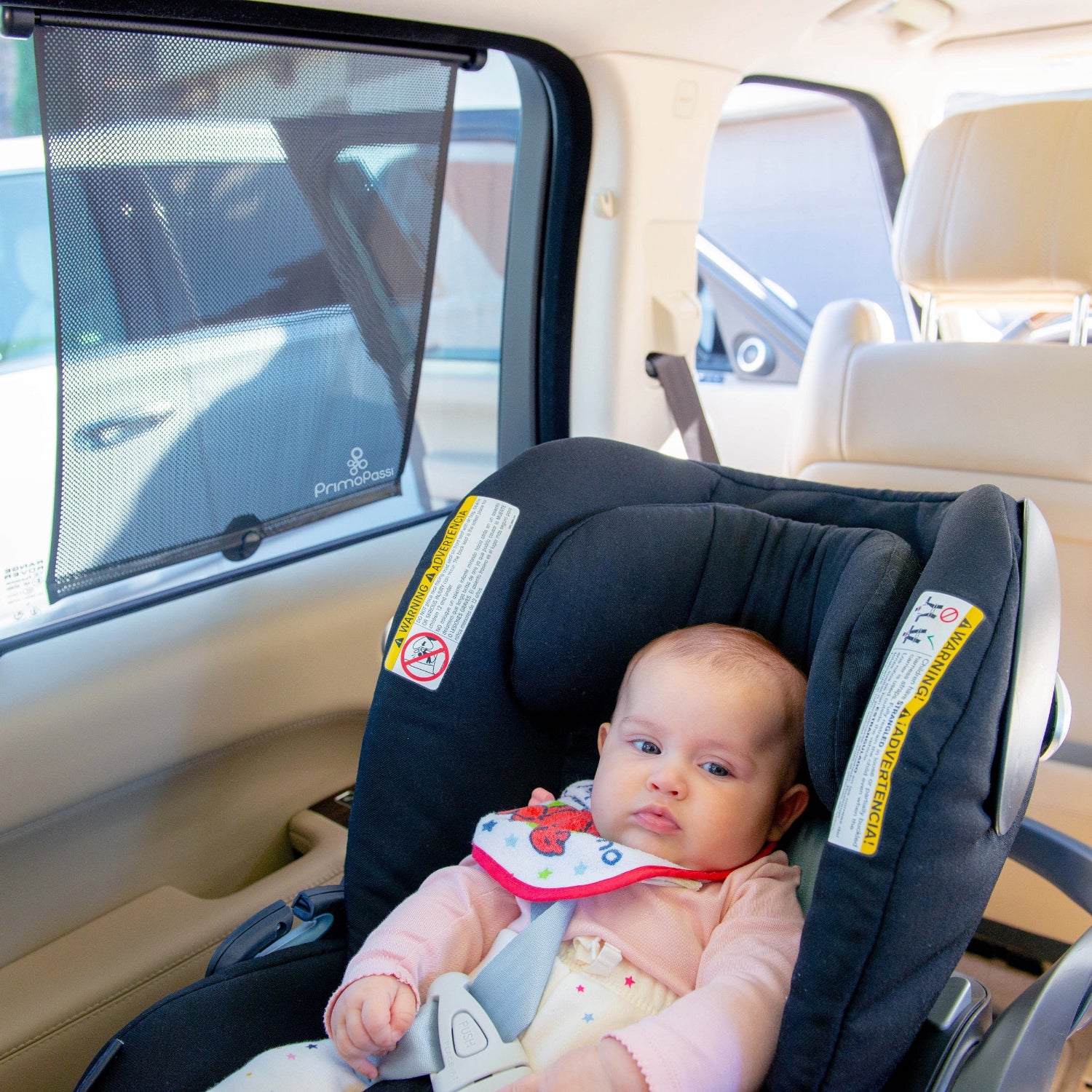 Baby in a car seat with a car window shade in a vehicle