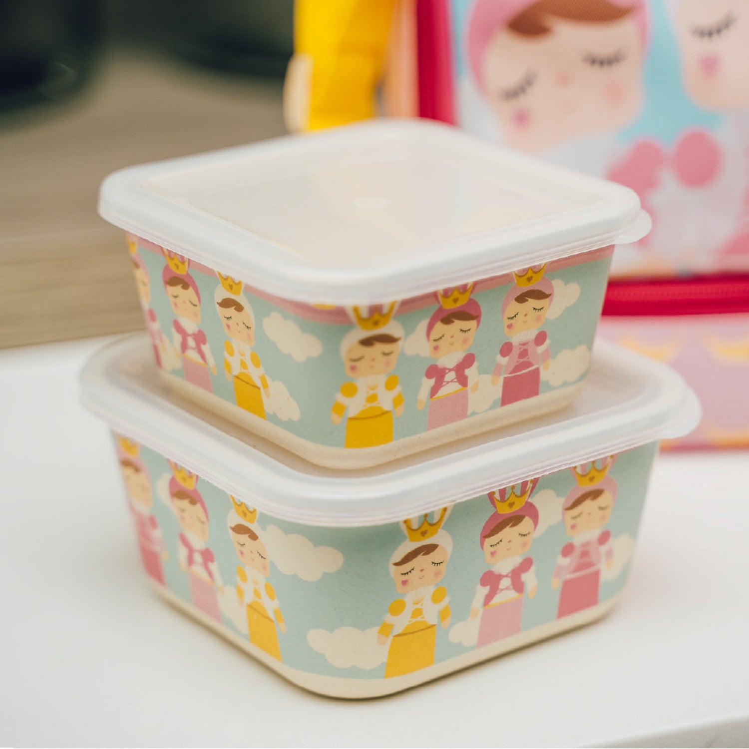 A set of two stacked rectangular food storage containers with metoo dolls