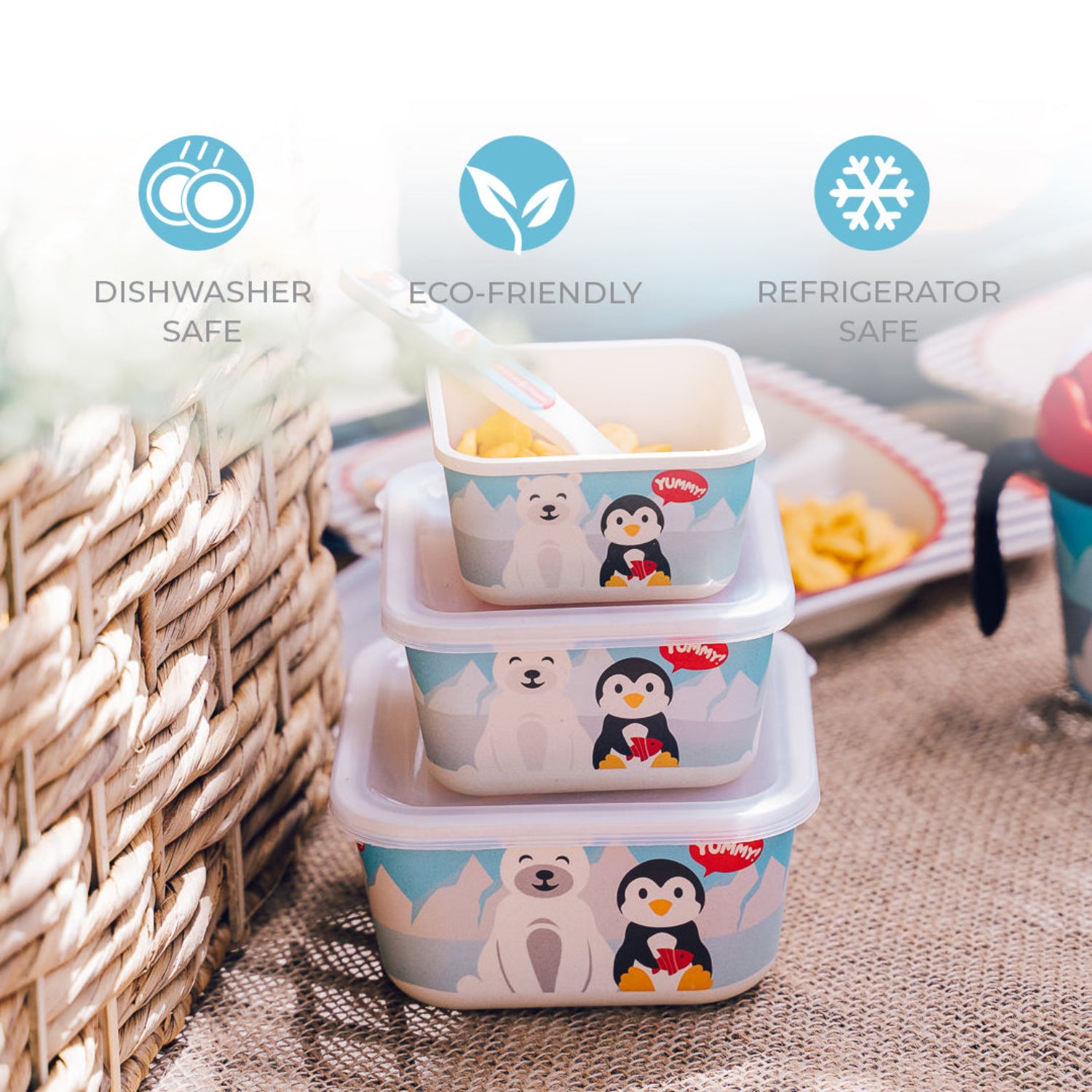 Three stacked square plastic storage containers with a polar bear and penguin print, shown on a woven mat with promotional text icons for dishwasher safe, eco-friendly, and refrigerator safe.