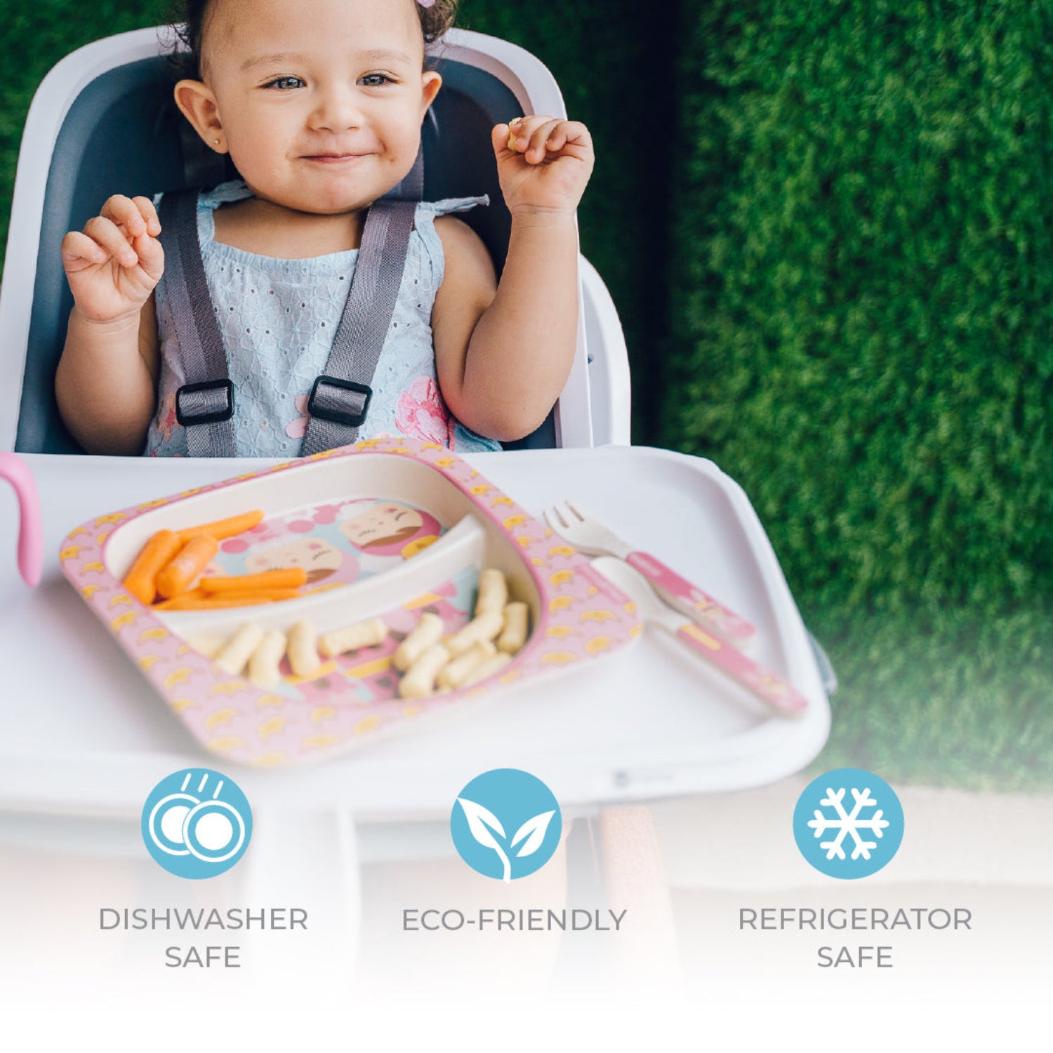 A young child with brown hair sitting in a high chair, eating carrots from a plate with a text: dishwasher safe, eco-friendly, refrigerator safe