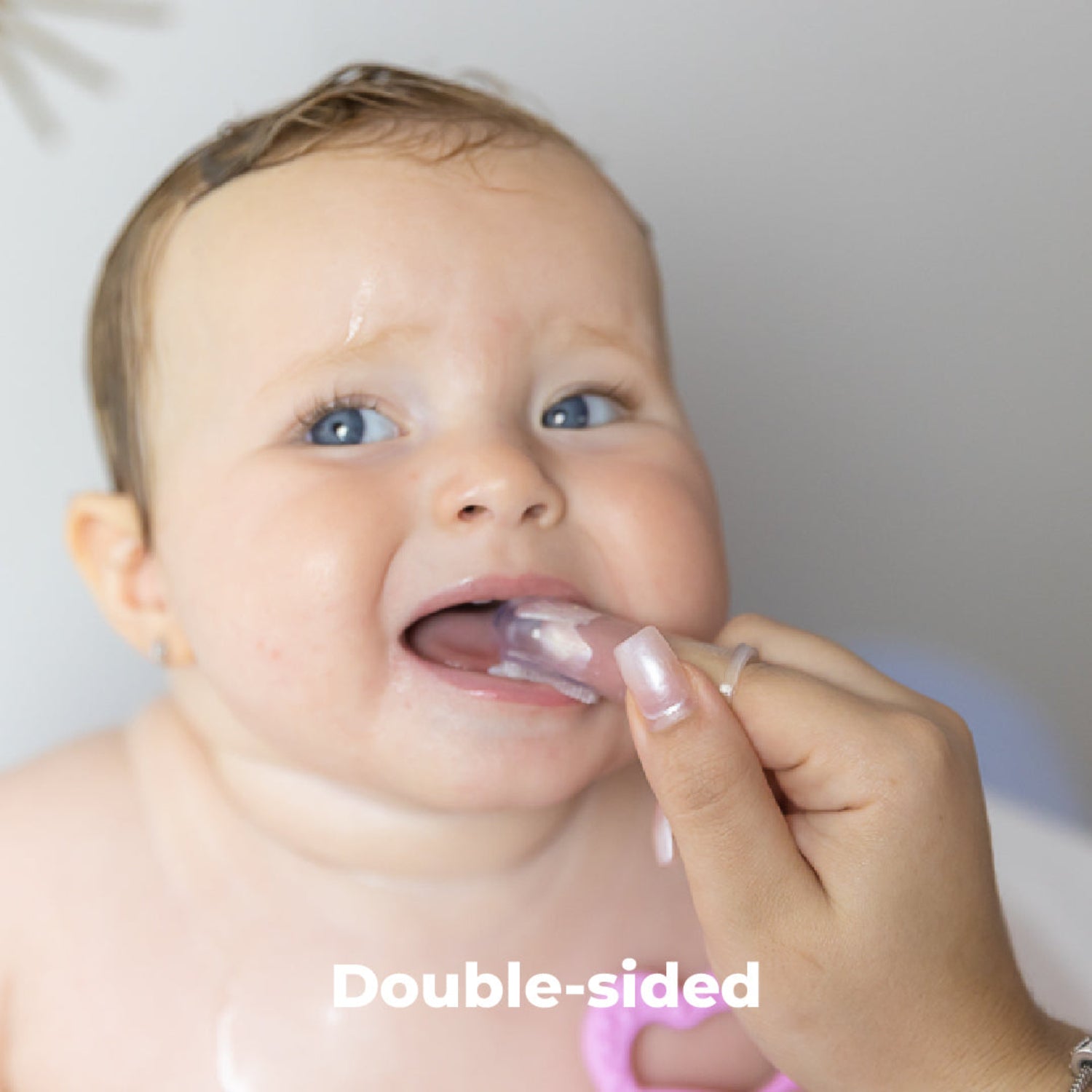 Parent using the Primo Passi double-sided silicone finger toothbrush to gently clean a baby's teeth and massage sensitive gums. Made from 100% food-grade silicone, the soft dual-sided design provides effective oral care while remaining gentle on delicate mouths. Suitable for babies 3 months and older.