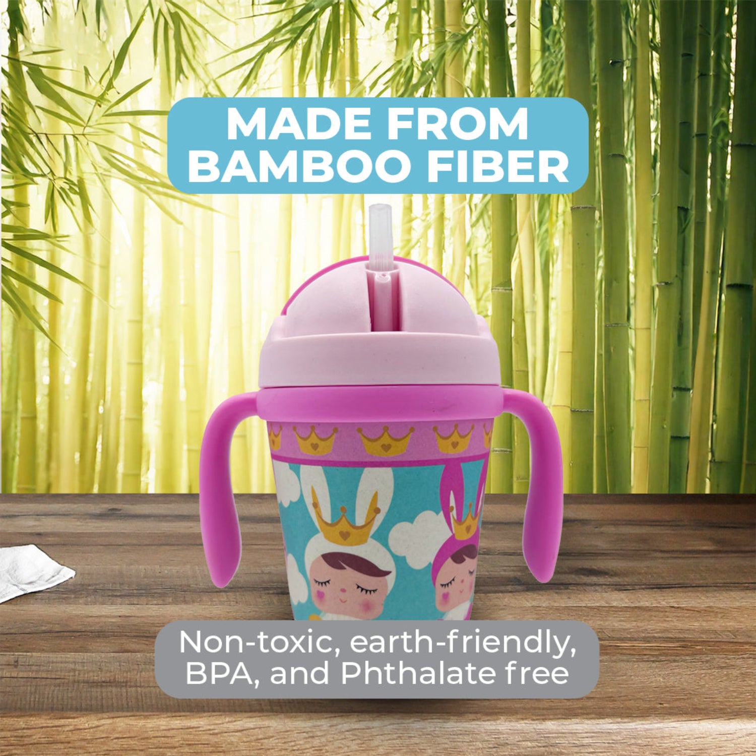Pink toddler training cup with two easy-grip handles, a soft straw, and a colorful princess-themed design featuring crowned characters, clouds, and crowns on a green and wood background.