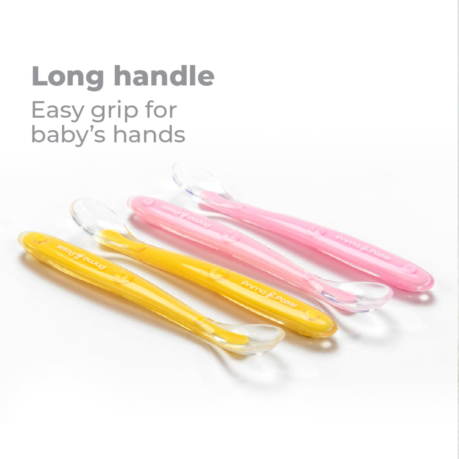 Four Primo Passi silicone baby spoons in pink and yellow with transparent spoon tips on a white background, highlighting the long handles for an easy grip for baby's hands.