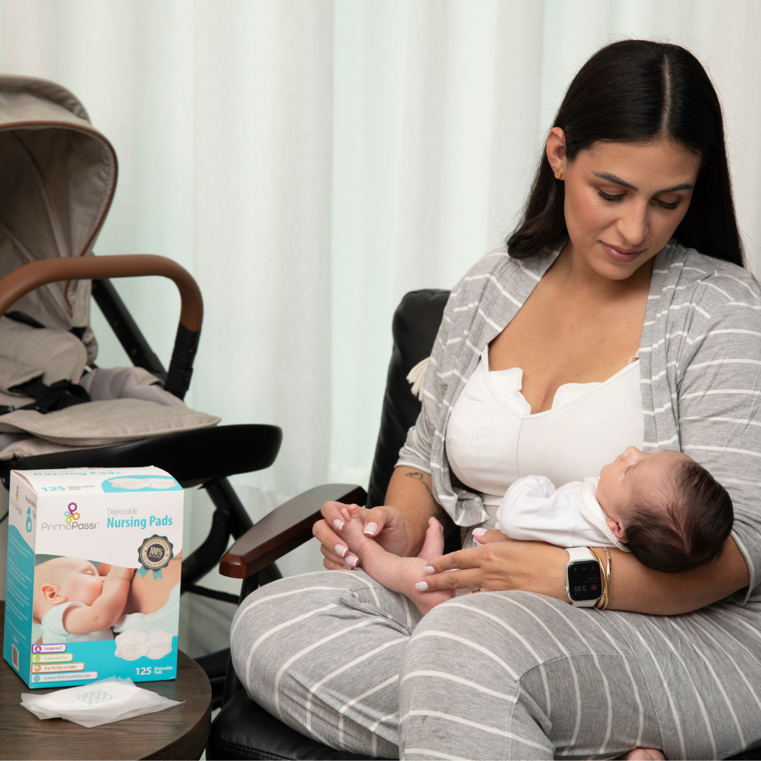 A mother breastfeeding her newborn while wearing Primo Passi disposable nursing pads for leak protection and comfort. A box of Primo Passi Nursing Pads and individually wrapped pads are displayed on a nearby table beside a stroller, highlighting convenient, ultra-absorbent breast care essentials for breastfeeding moms.