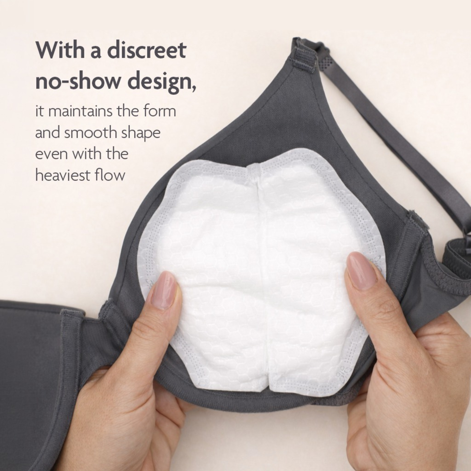 Close-up of a gray nursing bra with a Primo Passi disposable nursing pad placed inside the cup, demonstrating its discreet no-show design. The ultra-absorbent pad maintains a smooth, natural shape under clothing while providing reliable leak protection, even during heavy milk flow.