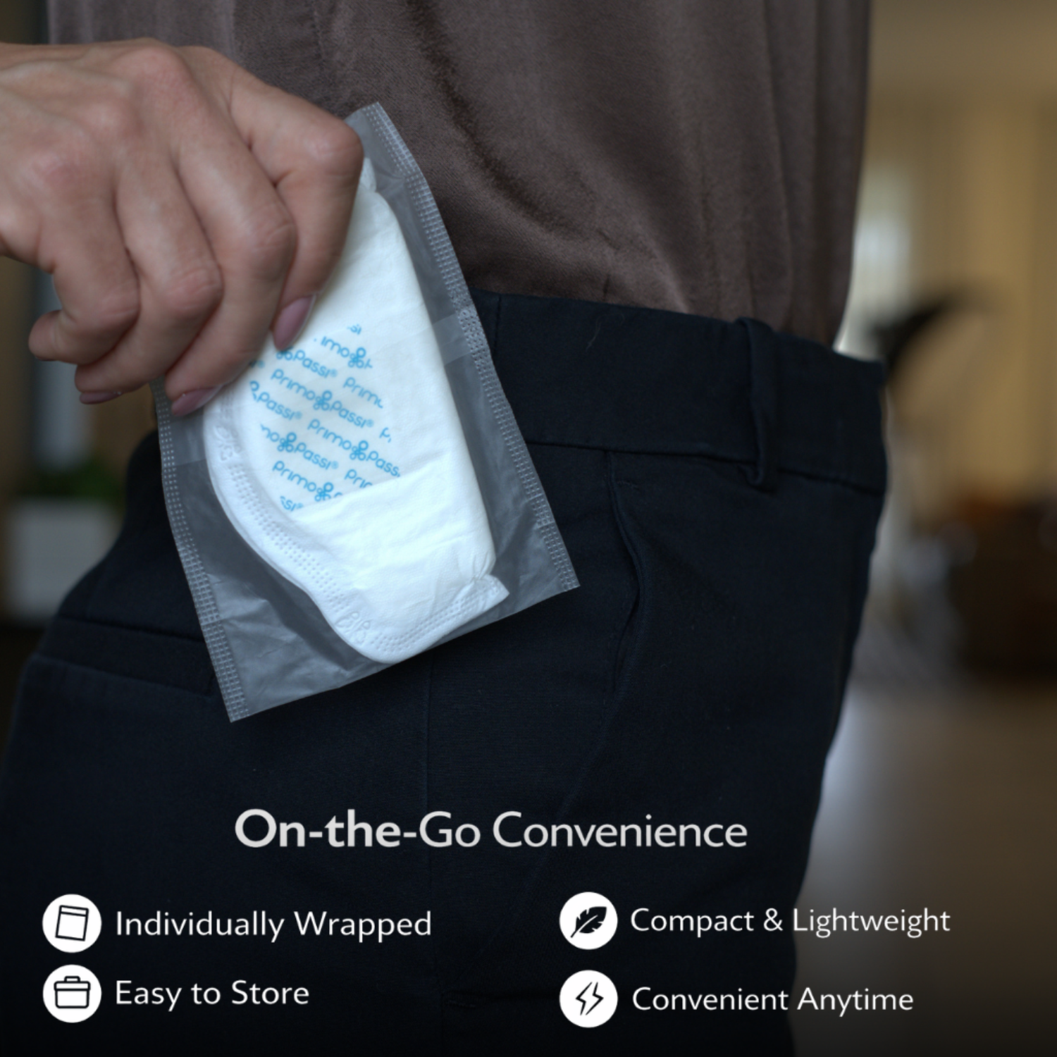 Close-up of a hand holding an individually wrapped Primo Passi disposable nursing pad while placing it into a back pocket. The compact, lightweight design makes it easy to carry, store, and use anytime, providing convenient leak protection for breastfeeding moms on the go.
