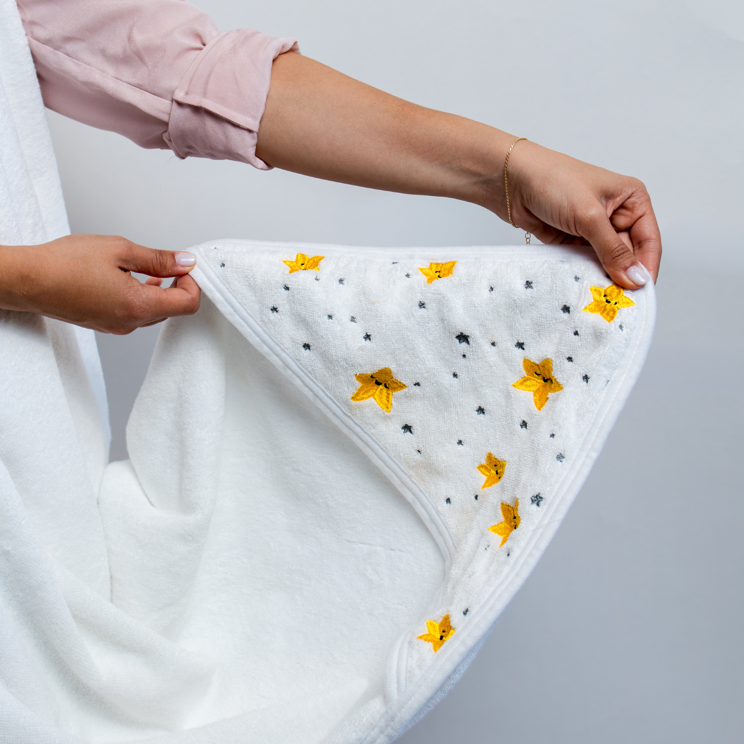 Close-up of the Primo Passi Terry Hooded Towel showcasing its built-in hood with charming yellow and gray embroidered stars. Made from ultra-soft, highly absorbent 100% cotton, the extra-large hood helps keep baby's head warm and cozy after bath time while adding a sweet, playful touch to the towel.