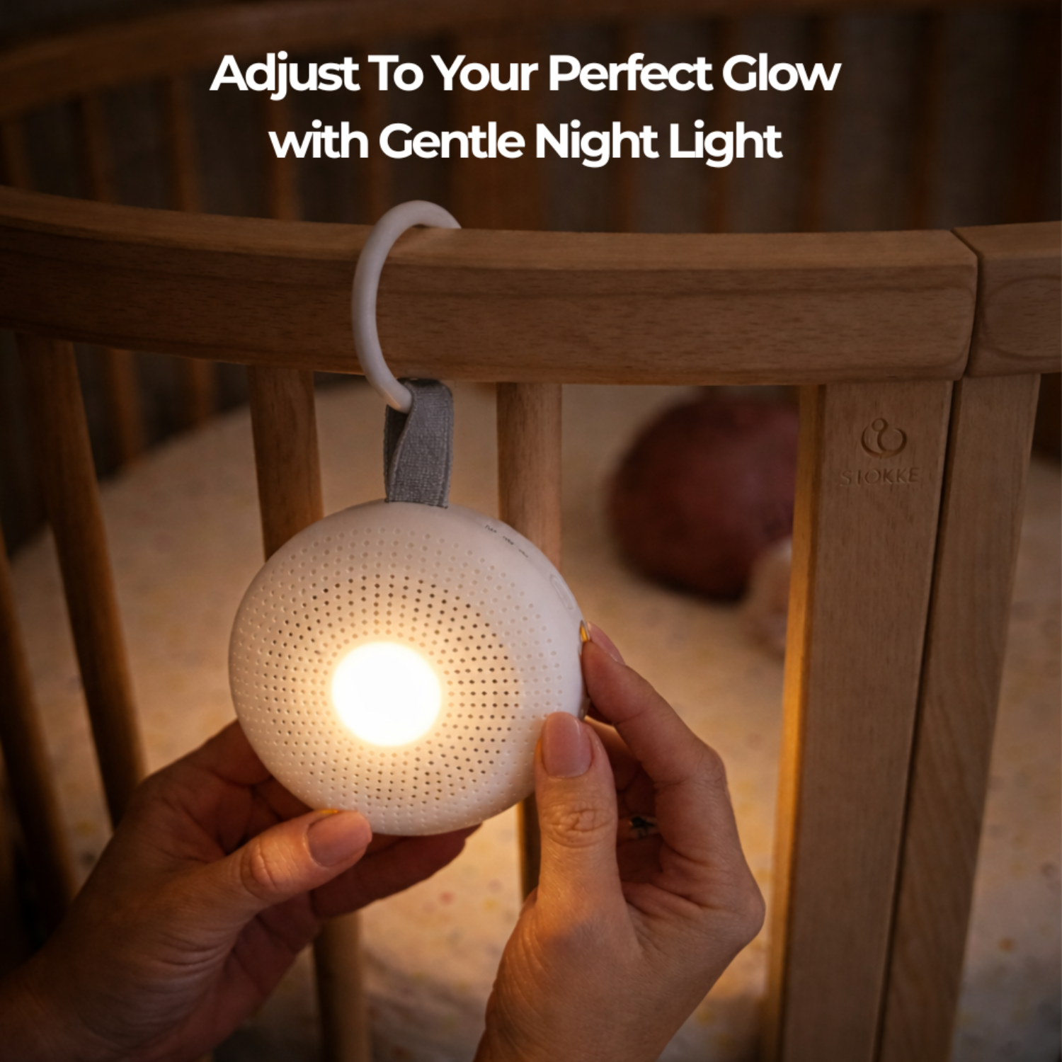 Hand holding a white portable sound machine for babies with the text 'Adjust To Your Perfect Glow with Gentle Night Light' above a wooden crib.